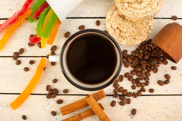 Vista superior de una taza de café con semillas de café marrón frescas, galletas de canela y mermelada de colores