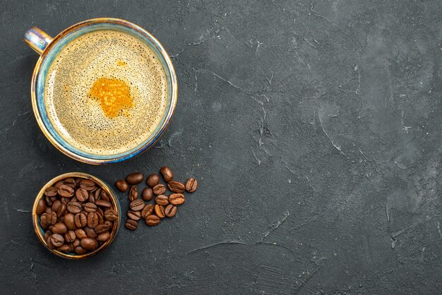 Vista superior de una taza de café con semillas de café sobre fondo oscuro aislado