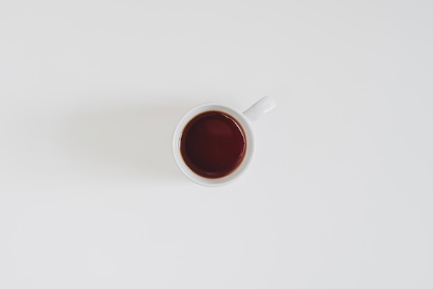 Vista superior de taza de café sobre superficie blanca
