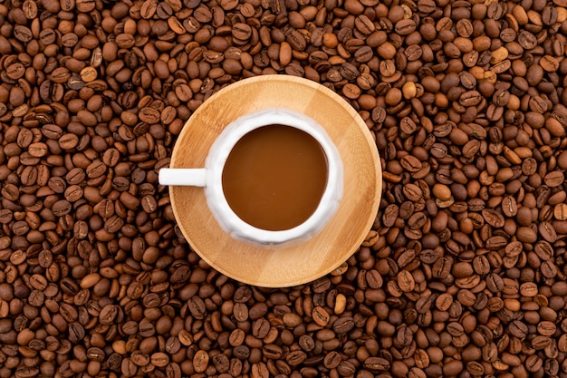 Vista superior de la taza de café en la superficie de granos de café tostado