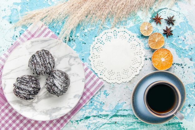 Vista superior de la taza de café con tortas de glaseado de chocolate sobre fondo azul claro pastel hornear galletas de tarta de azúcar dulce