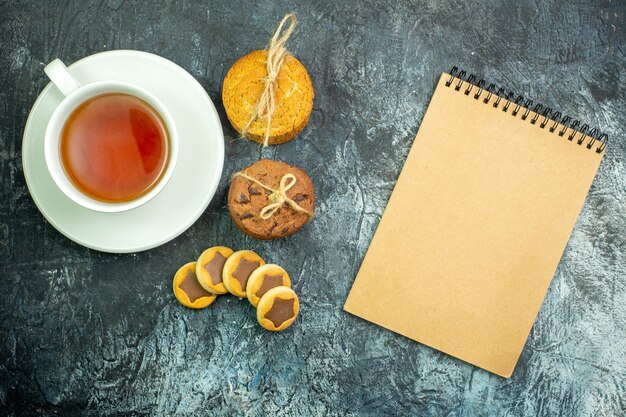 Vista superior de la taza de galletas de té galletas atadas con un cuaderno de cuerda sobre fondo gris