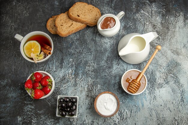 Vista superior de la taza de té con aceitunas y frutas en la superficie oscura de la comida del desayuno de la mañana