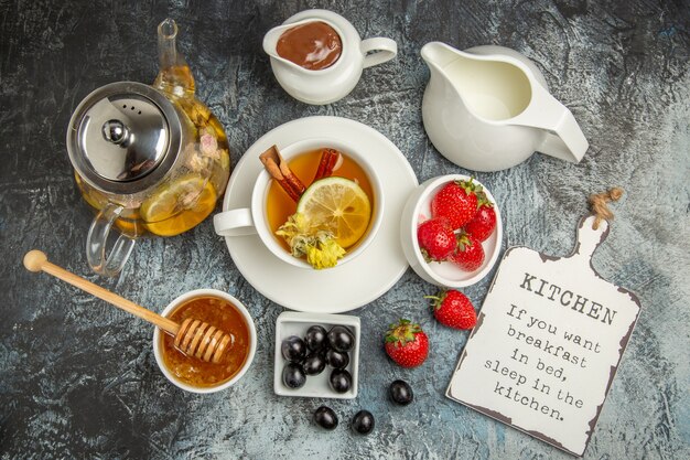 Vista superior de la taza de té con aceitunas y miel en la superficie oscura de la comida del desayuno de la mañana