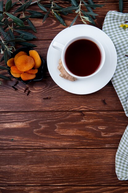 Vista superior de una taza de té con albaricoques secos en madera con espacio de copia