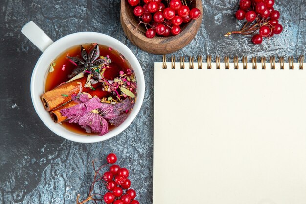 Vista superior de la taza de té con arándanos rojos sobre superficie oscura