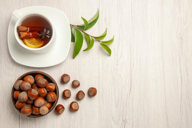 Vista superior de la taza de té con avellanas frescas en la ceremonia de aperitivos de nueces de té de escritorio blanco