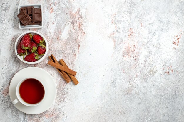 Vista superior de la taza de té con bayas de canela sobre superficie blanca