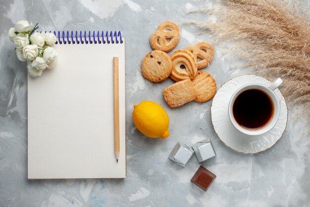 Vista superior de la taza de té caliente con chocolate, limón y galletas a la luz, dulces de galletas, té de chocolate, galletas dulces