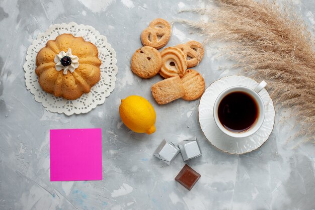 Vista superior de la taza de té caliente con chocolate, limón y galletas en el piso de luz dulce de galletas de té de chocolate y galletas dulces