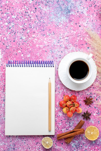 Foto gratuita vista superior de la taza de té con canela y bloc de notas sobre fondo rosa.