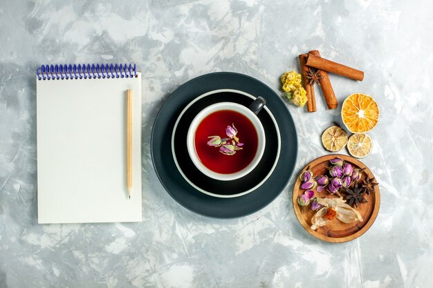 Vista superior de la taza de té con canela y flores en el escritorio blanco té flor bebida dulce