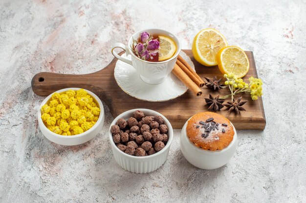 Vista superior de la taza de té con caramelos y rodajas de limón en el espacio en blanco