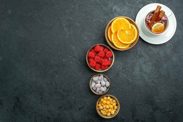 Foto gratuita vista superior de la taza de té con caramelos y rodajas de naranja en la superficie oscura confitura té dulce dulce