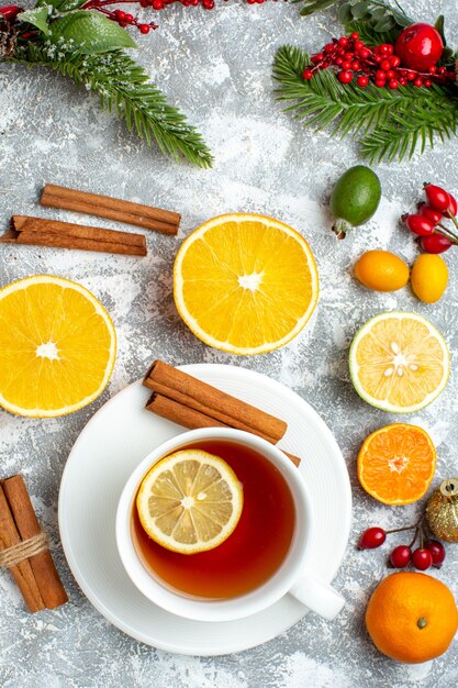 Vista superior de una taza de té cortado limones canela en rama mandarinas sobre fondo gris
