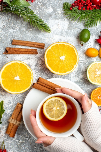 Vista superior de una taza de té cortado limones canela en rama sobre fondo gris