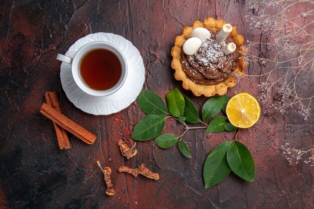 Vista superior de una taza de té con un delicioso pastelito en galletas de postre de galletas de mesa oscura