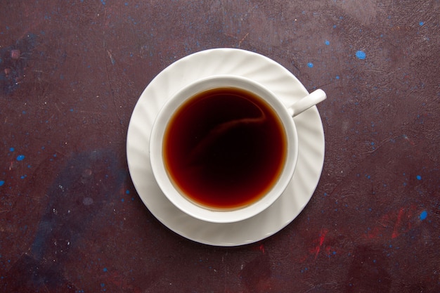 Vista superior de la taza de té dentro de la placa y la taza sobre fondo oscuro bebida de té dulce de fotografía en color