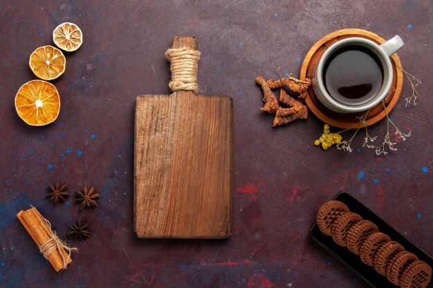 Vista superior de la taza de té dentro de la placa y la taza sobre fondo oscuro bebida de té dulce de fotografía en color