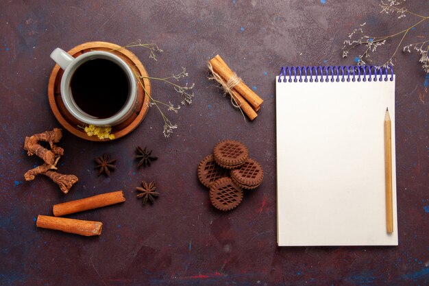 Vista superior de la taza de té dentro de la placa y la taza sobre fondo oscuro bebida de té dulce de fotografía en color