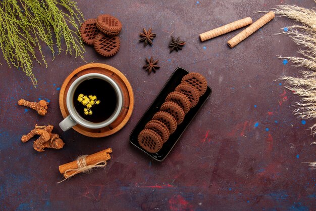 Vista superior de la taza de té dentro de la placa y la taza sobre fondo oscuro bebida de té dulce de fotografía en color