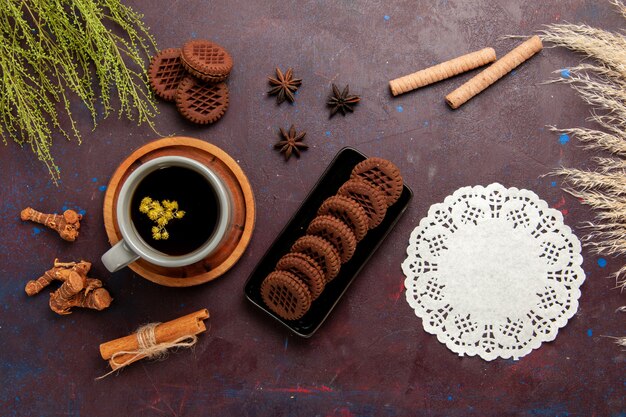 Vista superior de la taza de té dentro de la placa y la taza sobre fondo oscuro bebida de té dulce de fotografía en color