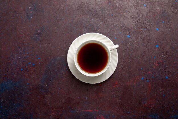 Vista superior de la taza de té dentro de la placa y la taza sobre fondo oscuro bebida de té dulce de fotografía en color