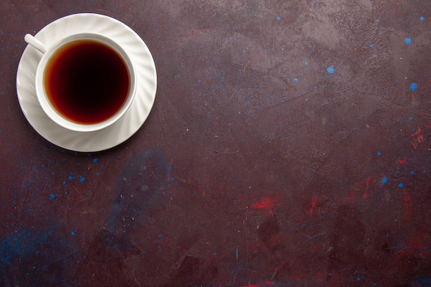 Vista superior de la taza de té dentro de la placa y la taza sobre fondo oscuro bebida de té dulce de fotografía en color