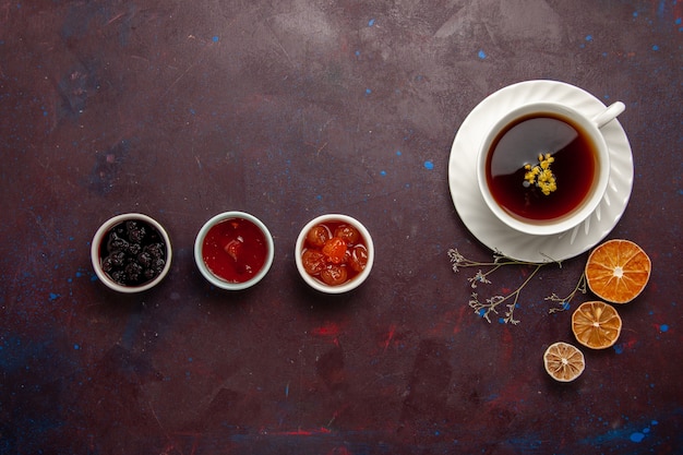 Vista superior de la taza de té dentro de la placa y la taza sobre fondo oscuro bebida de té dulce de fotografía en color