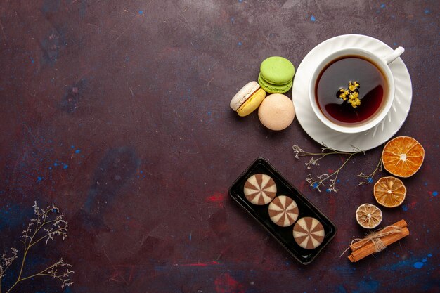 Vista superior de la taza de té dentro de la placa y la taza sobre fondo oscuro bebida de té dulce de fotografía en color