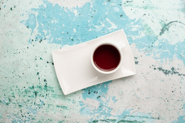 Vista superior de la taza de té dentro de la taza y el plato en el escritorio azul claro