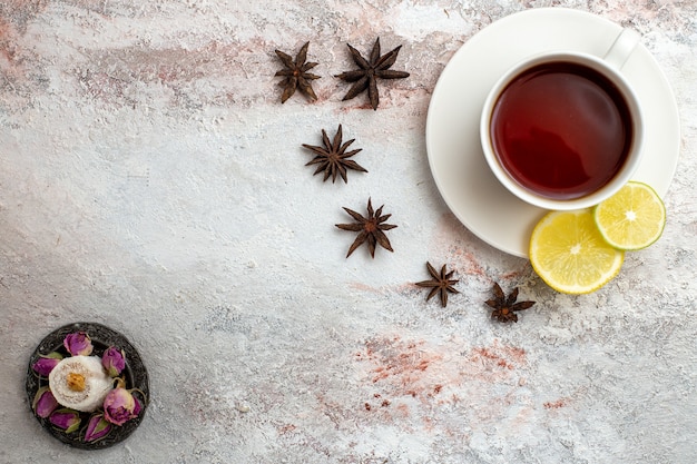 Vista superior de la taza de té dentro de la taza y el plato con limón sobre fondo blanco, bebida de té, ceremonia de desayuno dulce