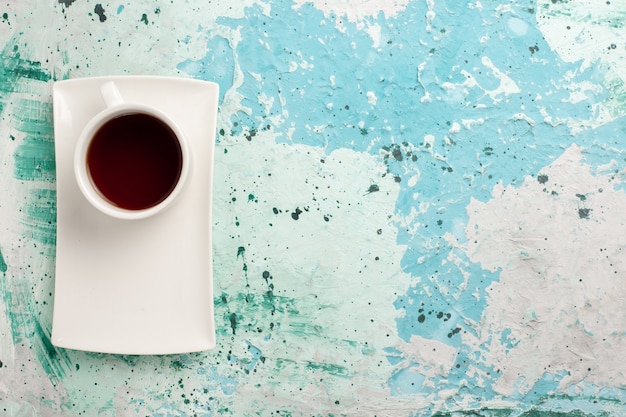 Vista superior de la taza de té dentro de la taza y el plato sobre una superficie azul claro