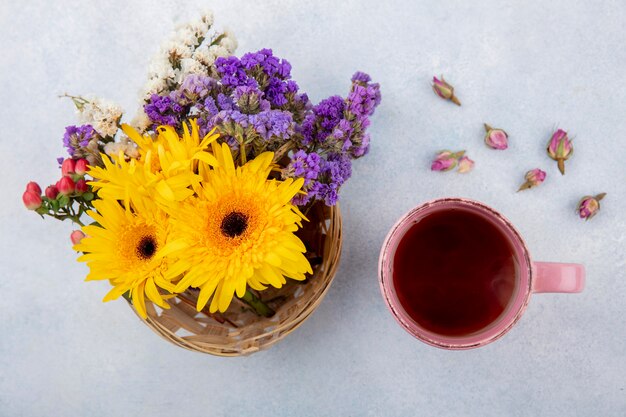 Foto gratuita vista superior de la taza de té y flores en la canasta y en blanco