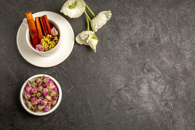 Vista superior de la taza de té con flores y canela sobre un fondo gris color del té sabor del arco iris