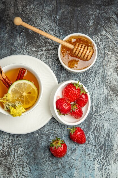 Vista superior de una taza de té con fresas y miel en la superficie oscura de la baya de té de frutas