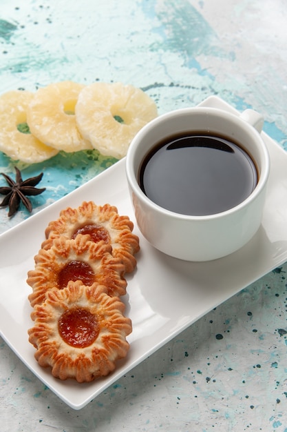 Foto gratuita vista superior de una taza de té con galletas y anillos de piña secos sobre una superficie azul claro