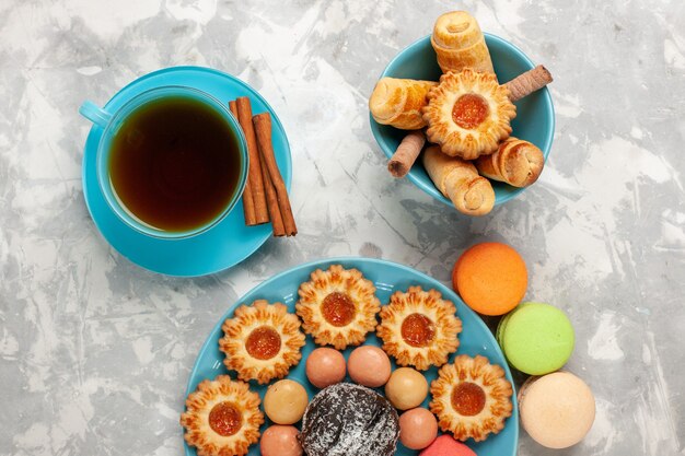 Vista superior de la taza de té con galletas bagels y macarons en la superficie blanca