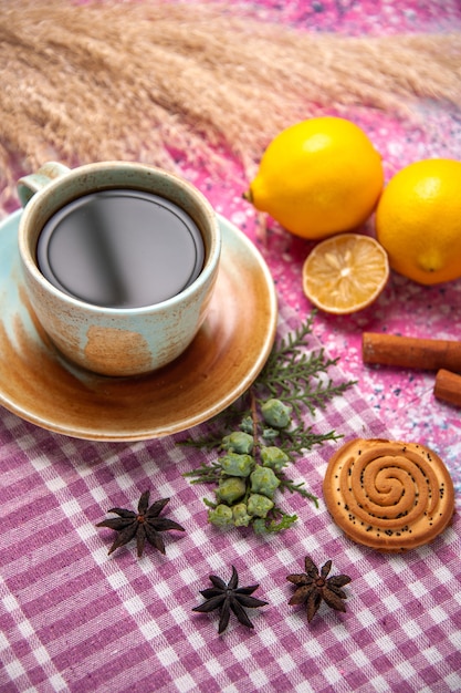 Foto gratuita vista superior de la taza de té con galletas de canela y limones en el escritorio rosa.