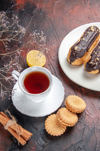 Vista superior de la taza de té con galletas y canutillos en el dulce de la galleta del té del azúcar de mesa oscuro