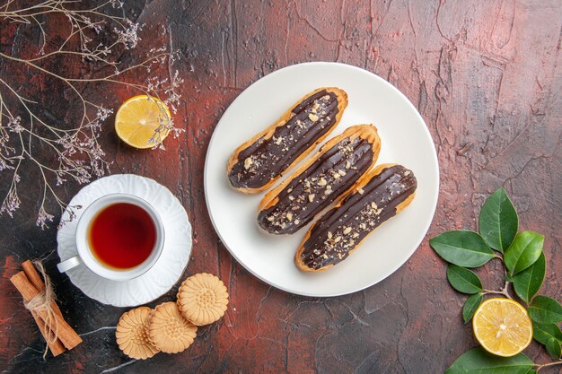 Vista superior de la taza de té con galletas y canutillos en el dulce de la galleta del té del azúcar de mesa oscuro