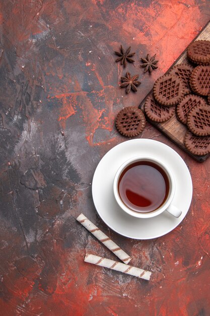 Vista superior de la taza de té con galletas choco en la mesa oscura ceremonia de color té oscuro