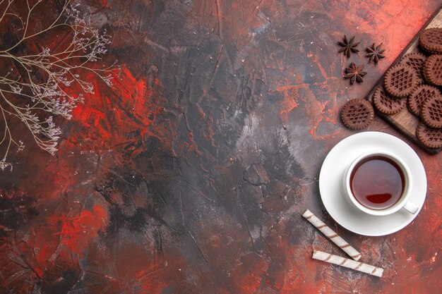 Vista superior de la taza de té con galletas choco en la mesa oscura ceremonia de color té oscuro