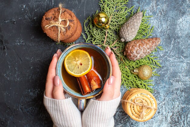 Vista superior de la taza de té con galletas dulces y conos sobre fondo claro-oscuro