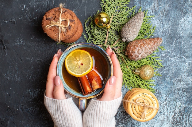 Vista superior de la taza de té con galletas dulces y conos sobre fondo claro-oscuro