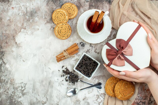 Vista superior taza de té con galletas dulces y presente sobre fondo claro día de san valentín pareja galleta de azúcar color amor matrimonio