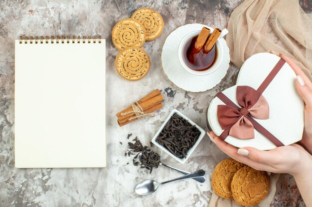 Vista superior taza de té con galletas dulces y presente sobre fondo claro día de san valentín pareja sintiendo galleta color amor matrimonio