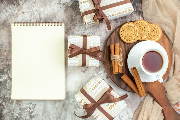 Vista superior taza de té con galletas dulces y regalos sobre fondo claro ceremonia de descanso de galletas color de pastel de café con azúcar