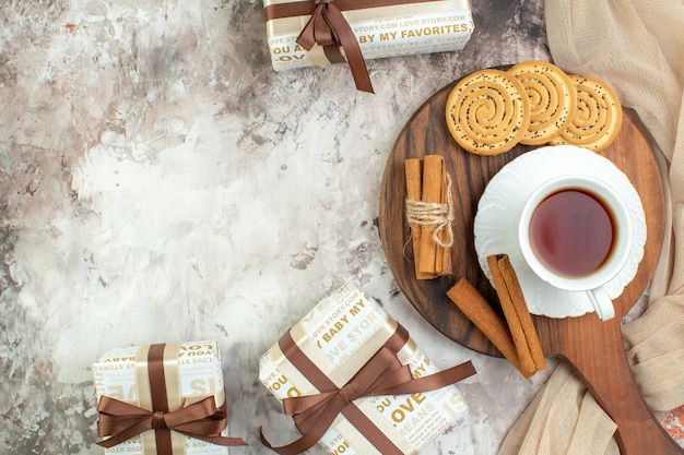 Vista superior taza de té con galletas dulces y regalos sobre fondo claro ceremonia de galletas color de pastel de café con azúcar