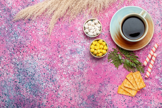 Vista superior de la taza de té con galletas y dulces en superficie rosa